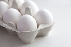Fresh white eggs in cardboard egg box.