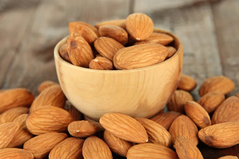 Almond in wooden bowl, on wooden background