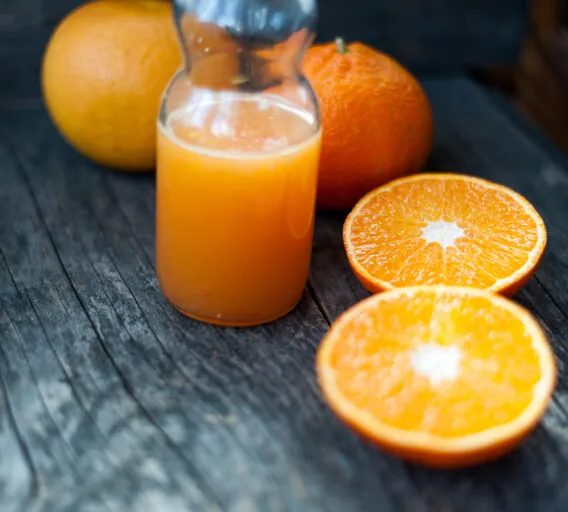 Fresh orange juice and fresh oranges on a wooden table