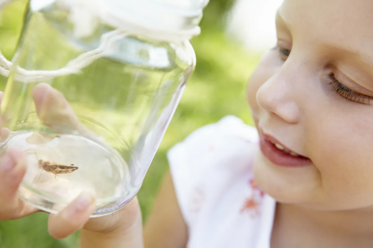 Little girl with cricket in a jar