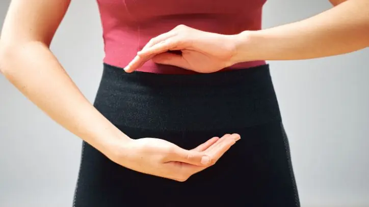 Woman holding her hands in front of her stomach