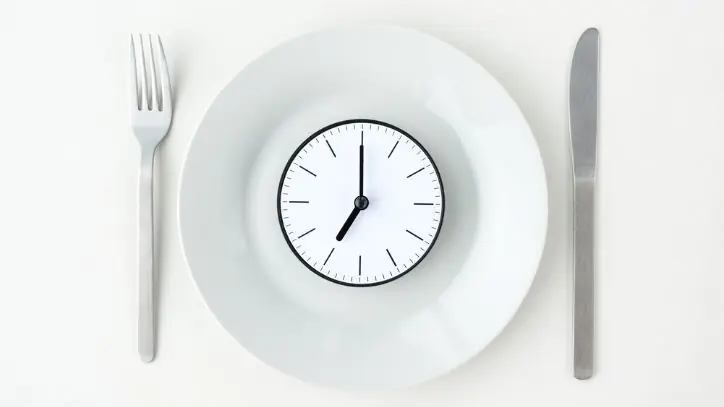 Table setting with a clock sitting in the middle of the plate