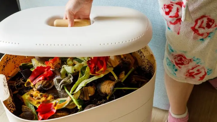 Woman lifting the lid off of a compost bin