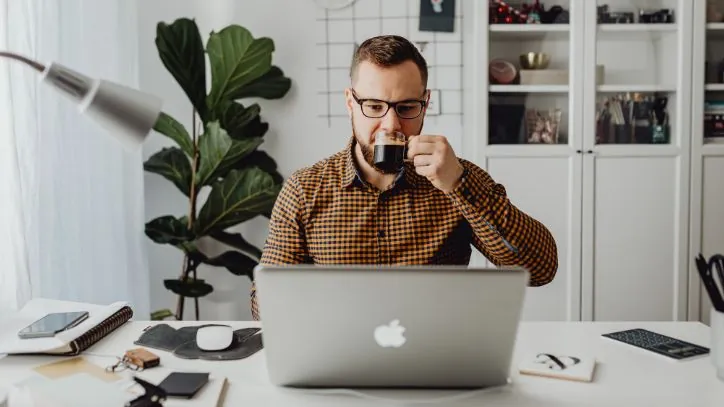 Man drinking coffee while sitting behind a computer