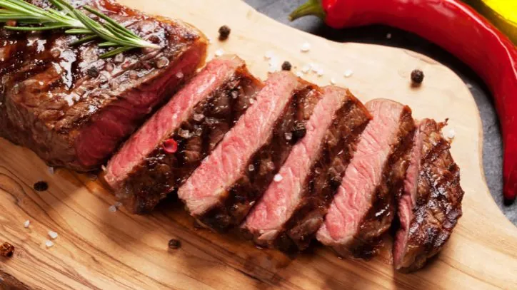 Grilled steak that has been sliced up on a cutting board