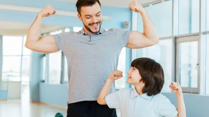 Father and son holding their arms up to show their muscles