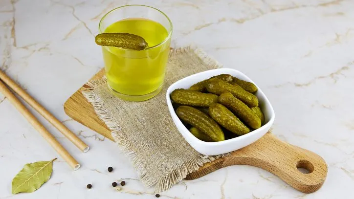 Glass of pickle juice on a cutting board