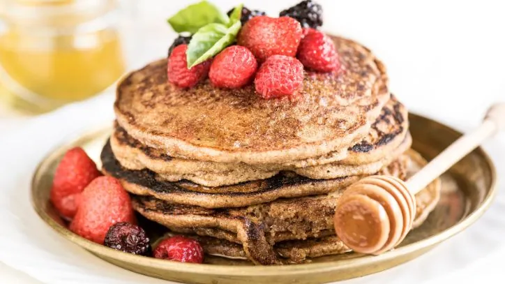 stack of buckwheat pancakes with fruit on top