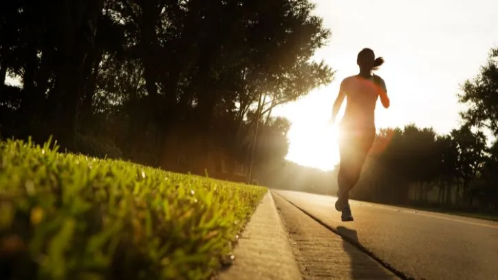 Woman jogging with the sun rising behind her