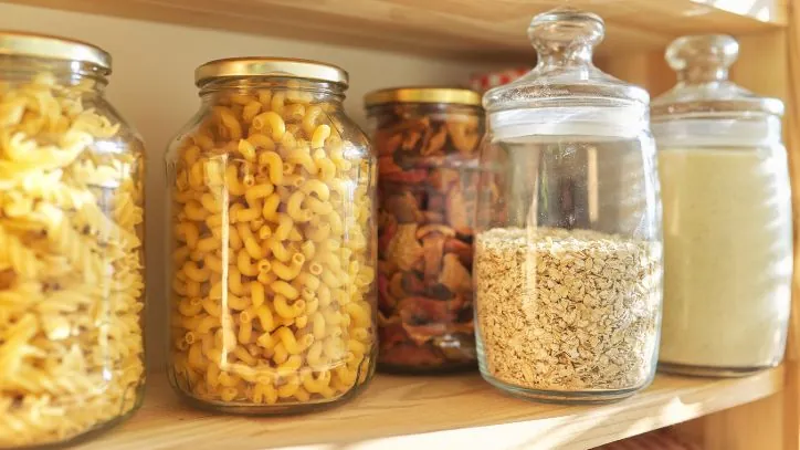 Pantry shelf filled with jars of pasta and various grains