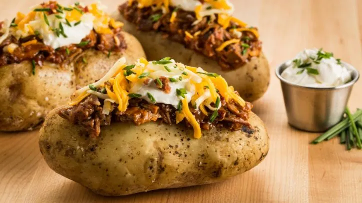 Close up of 3 BBQ loaded baked potatoes