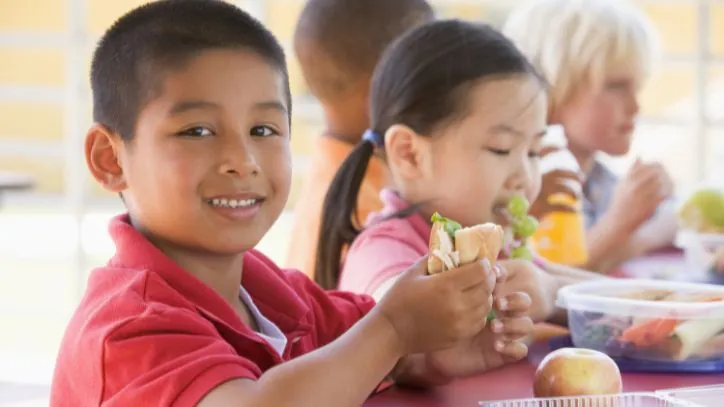 Child eating a school lunch with other students