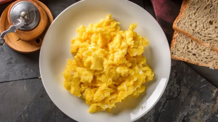 Plate of scrambled eggs with toast next to it