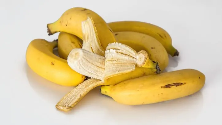 pile of bananas with one opened to reveal the inside