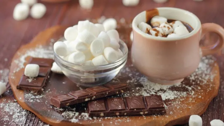 wooden tray holding a mug of hot chocolate, chocolate bars and a bowl with marshmallows