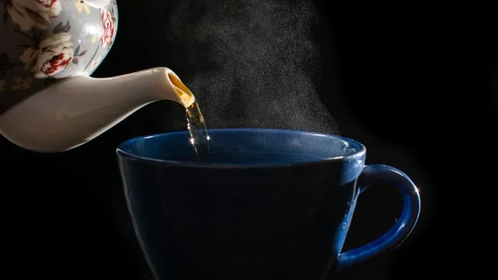 chamomile tea being poured from a teapot into a teacup