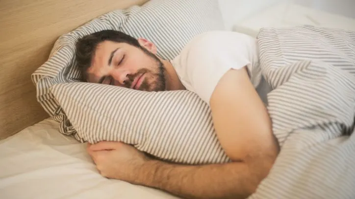 man sleeping in a bed with striped sheets