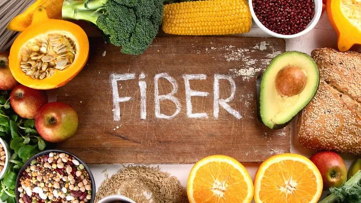 Cutting board with the word "FIBER" written in the middle of it, surrounded by high fiber foods