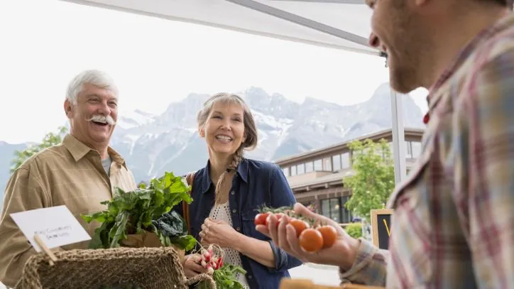 A couple speaking with a Farmer at the Farmer's Market