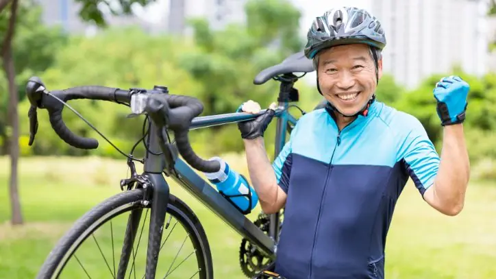 Cyclist holding up his bike and smiling at the camera