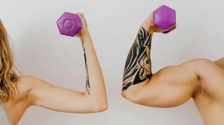 A male and female flexing their arms while lifting weights